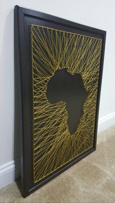 a black and gold framed art piece with the shape of africa on it's side