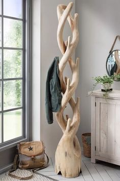 a coat rack made out of driftwood stands next to a window in a room