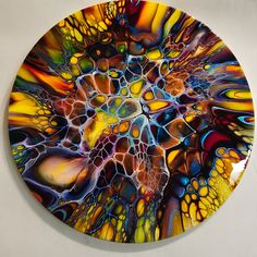 an abstract painting on a white wall in the shape of a circular plate with multicolored shapes