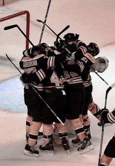 a group of hockey players huddle together in the middle of an ice rink while wearing black and white uniforms