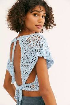 a woman wearing a blue crochet top with open back