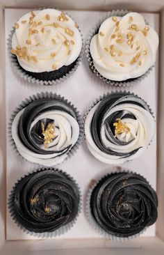 four cupcakes with white frosting and gold sprinkles in a box