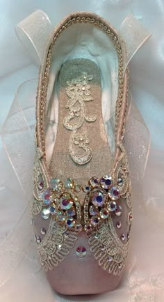 a close up of a pair of shoes on a white cloth covered surface with beads and sequins