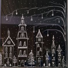 the window is decorated with white frosting and hand drawn christmas trees, houses, and snowflakes