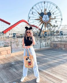 a woman in mickey mouse ears is talking on her cell phone while standing on a boardwalk