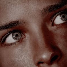 a man's face with blue eyes and black hair is shown in this close up photo