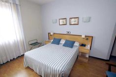 a bed room with a neatly made bed and two pictures on the wall above it