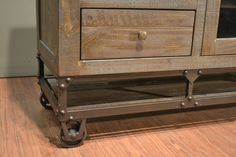 an old wooden cabinet with metal handles and wheels on the bottom, sitting on a hard wood floor