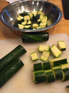 cucumbers cut up on a cutting board next to a metal bowl and knife