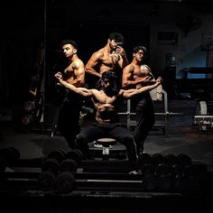 a group of men standing on top of a bench in front of dumbbells