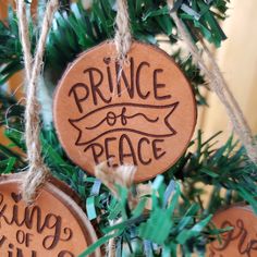 three wooden ornaments hanging from a tree with the words prince of peace and king of kings on them