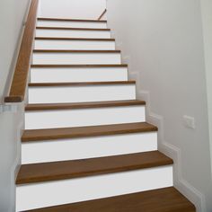 there is a white stair case with wood treads on the bottom and bottom steps