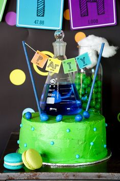 a science themed birthday cake with blue and green frosting on the bottom, topped with an experiment bottle