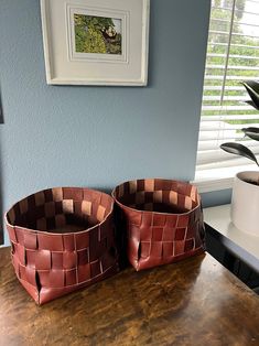 two brown baskets sitting on top of a wooden table