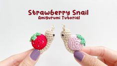 two small crocheted fruits are being held by someone's hands with the words strawberry snail on them