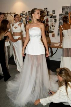 a woman in a white dress standing next to other women