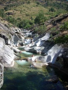 several people are swimming in the water near some rocks