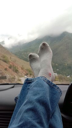 someone is sitting in the passenger seat of a car with their feet on the dashboard