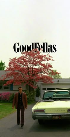 a man walking down a street next to a yellow car with the words goodfellas on it