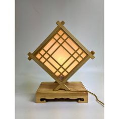 a wooden table lamp sitting on top of a wooden stand with a white light in the middle