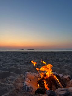 a campfire on the beach at sunset