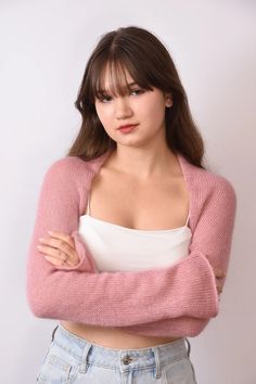 a young woman with her arms crossed posing for the camera in front of a white wall