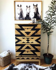 a black and white dresser with two horses on it next to a potted plant