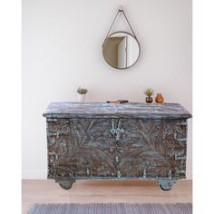 an old chest is sitting in front of a wall with a mirror on it and plants