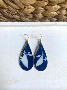 These cyanotype earrings feature photographic prints made from real botanicals, the sun and water! The prints were created by placing botanicals on watercolor paper coated in photo-reactive chemicals then exposed directly to the sun. The result this stunning Prussian Blue background contrasted by the white silhouettes of the botanicals. Every print is one of a kind and there are slight variations from piece to piece.  The cyanotype print was then sealed and placed in an antique gold bezel, and c Cyanotype Earrings, Cyanotype Print, Alternative Photography, Cork Material, Prussian Blue, Sun And Water, Unique Earrings, My Flower, Flower Earrings