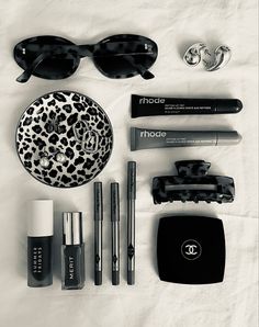 black and white photograph of various items including sunglasses, lipstick, eyeglasses