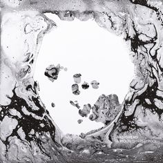 black and white photograph of water with rocks in the bottom right hand corner, surrounded by bubbles