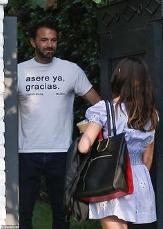 a man and a woman walking down the street with a handbag on their shoulder