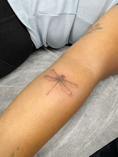 a small dragonfly tattoo on the arm