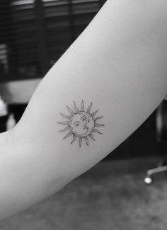 a small sun and moon tattoo on the left arm, it is black and white