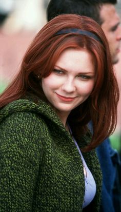 a woman with red hair is smiling at the camera