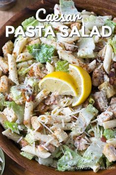 pasta salad with chicken, lettuce and lemon wedges in a wooden bowl