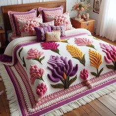 a bed covered in pink and yellow flowers on top of a wooden floor next to a window