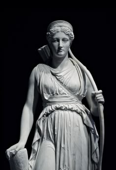 a black and white photo of a statue of a woman with a staff in her hand