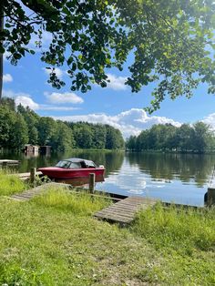 a red boat sitting on top of a lake next to a dock