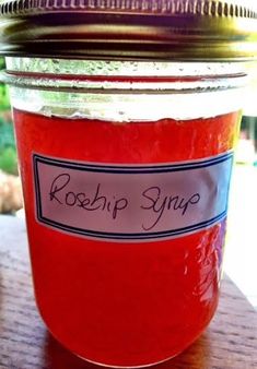 a jar filled with red liquid sitting on top of a wooden table