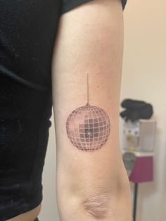 a woman's arm with a tattoo on it that has an image of a ball