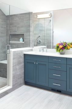 a bathroom with blue cabinets and a white sink in the middle is decorated with flowers