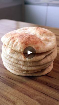 a stack of pita bread sitting on top of a wooden table