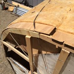 an unfinished wooden boat sitting on top of a pile of wood