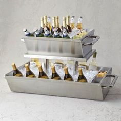 three tiered trays holding bottles of wine and ice cubes on white marble countertop