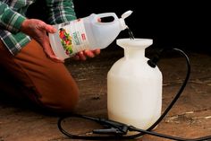 a person kneeling down next to a white jug with a black hose connected to it