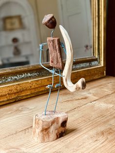 a wooden sculpture with a piece of wood on it's side and a mirror in the background