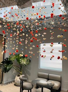 a room with chairs, tables and flowers hanging from the ceiling