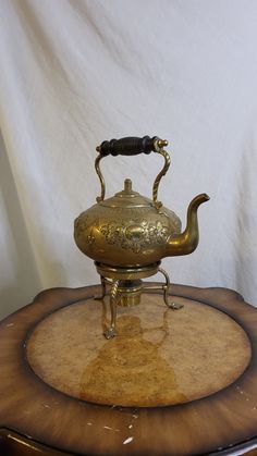 an antique brass teapot on top of a wooden table