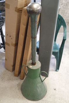 a green vase sitting on top of a cement floor next to boxes and other items